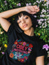 Black activist T-shirt with a floral embroidered-style design and the words “Obey Nothing” in bold, bright lettering.